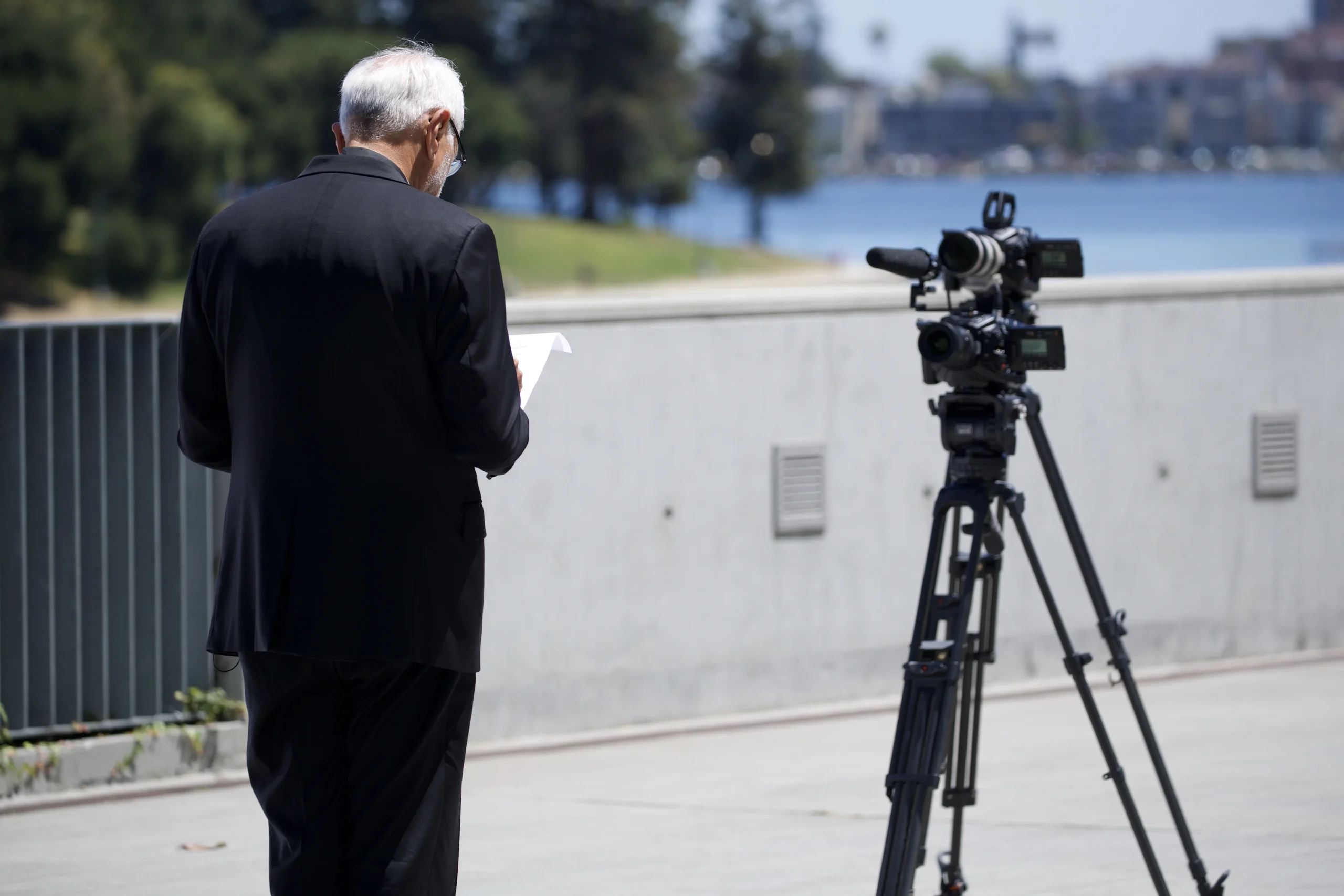 A priest walking beside a lake reviewing his notes