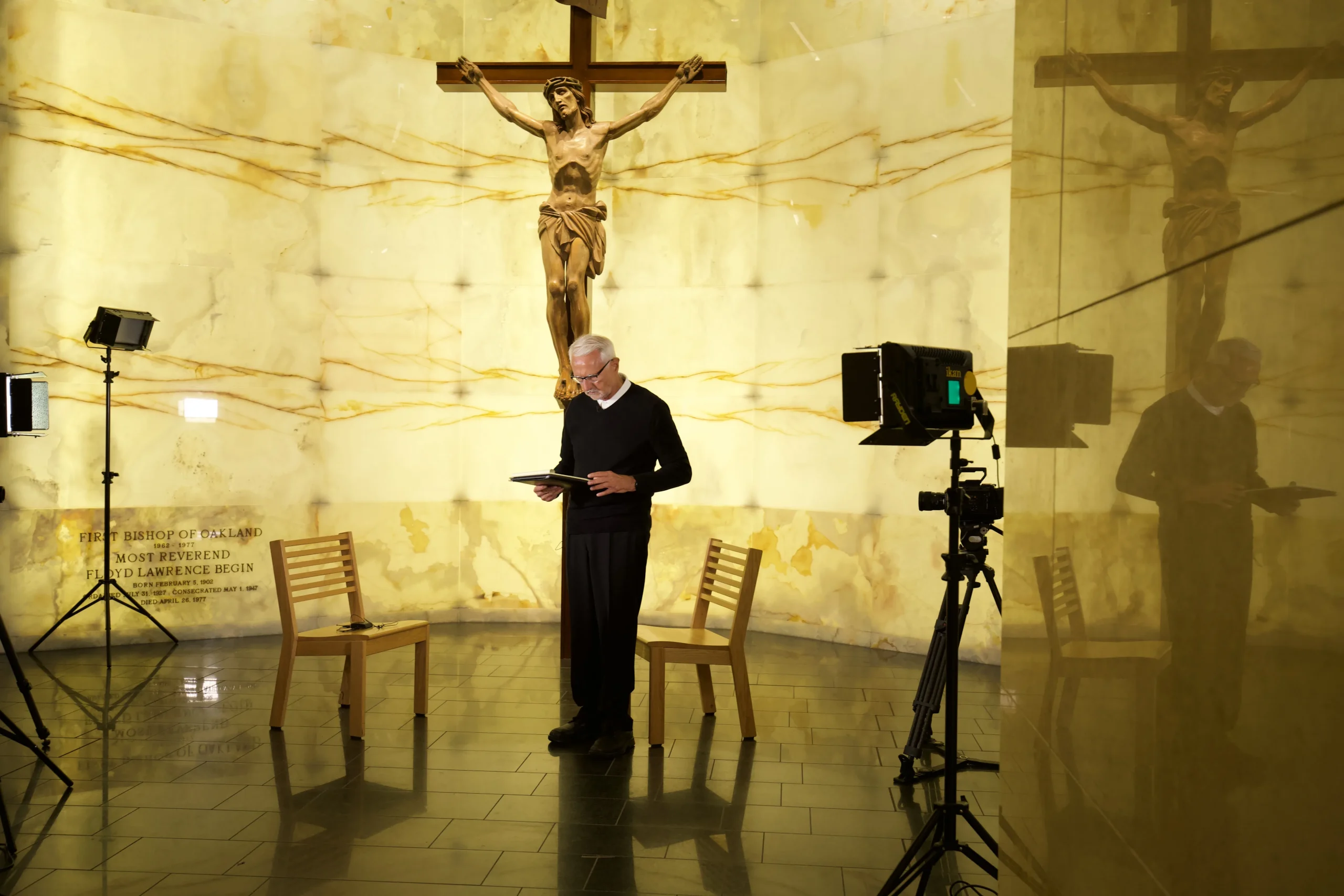 A priest before a crucifix in a crypt